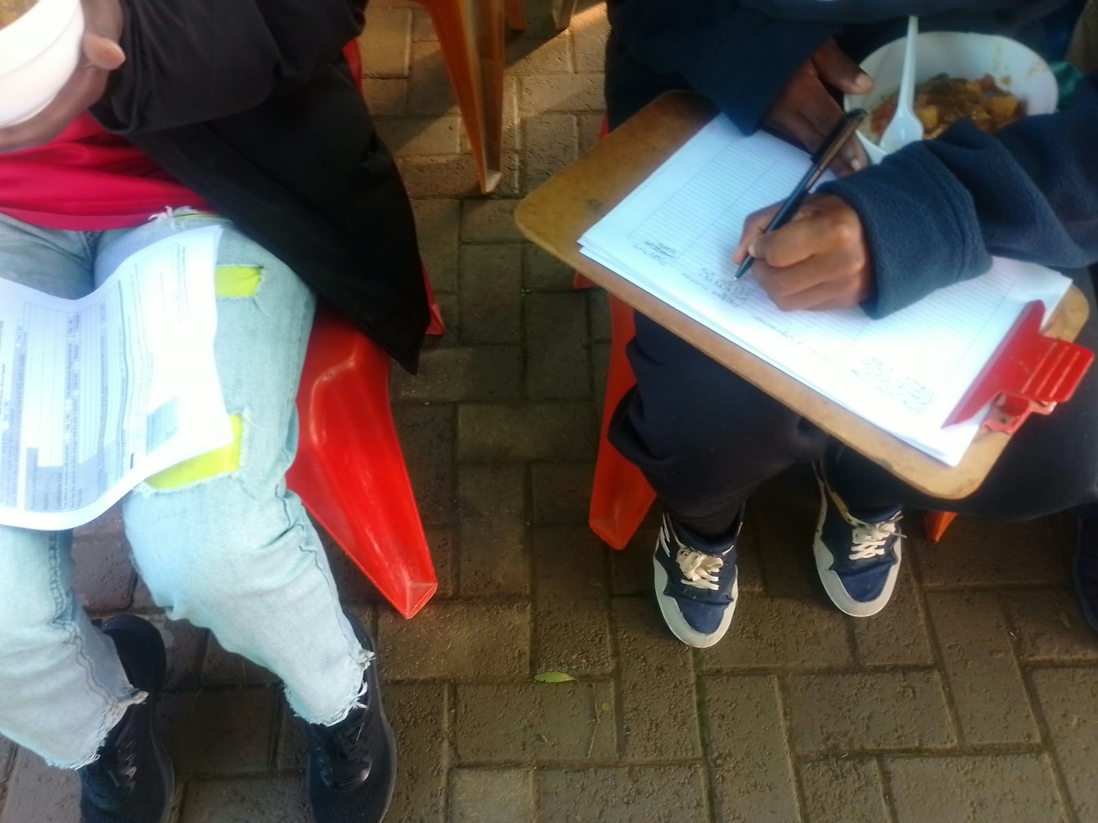 A programme participant completing the attendance register while seated with another participant