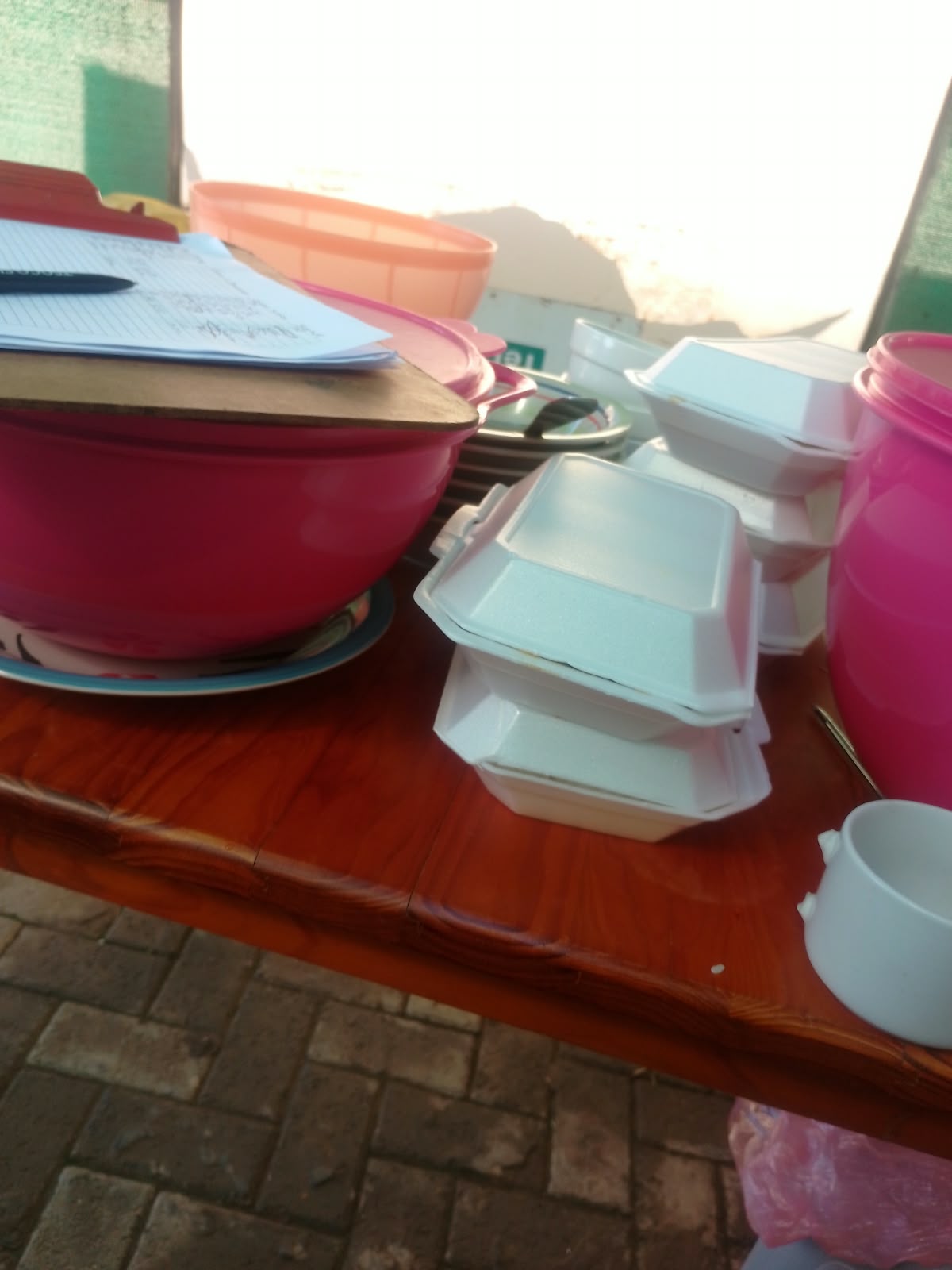 Prepared takeaway meal containers arranged beside serving bowls and a programme register