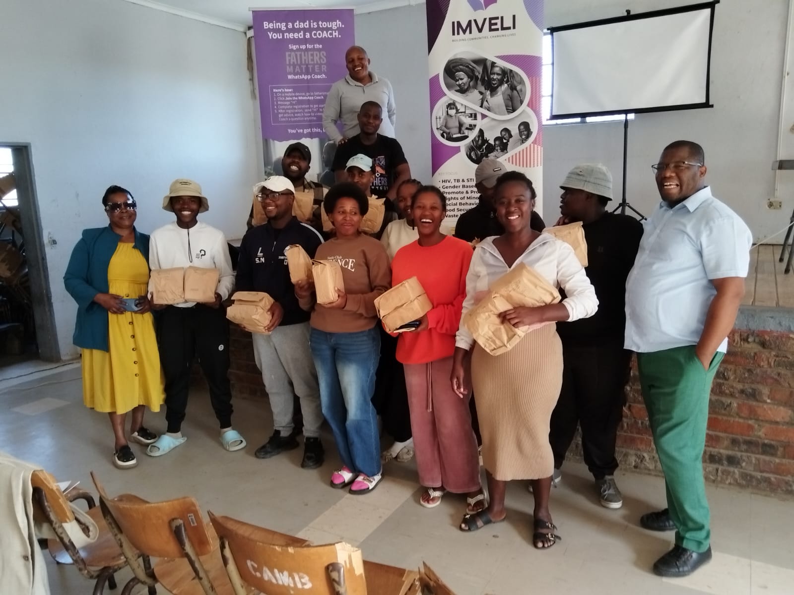 Fathers Matter workshop attendees with IMVELI banner and gift bags